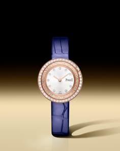 Piaget Possession watch with a round white gold case, a bezel set with diamonds, and a silver dial featuring diamond hour markers. It has two silver hands and is paired with a light blue alligator leather strap.