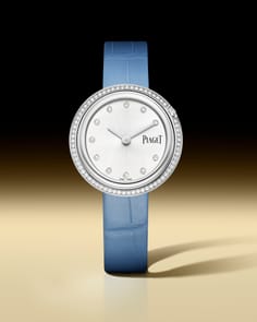 Piaget Possession watch with a round white gold case, a bezel set with diamonds, and a silver dial featuring diamond hour markers. It has two silver hands and is paired with a light blue alligator leather strap.