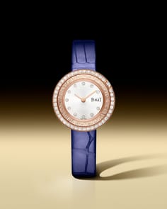 Piaget Possession watch with a round white gold case, a bezel set with diamonds, and a silver dial featuring diamond hour markers. It has two silver hands and is paired with a light blue alligator leather strap.